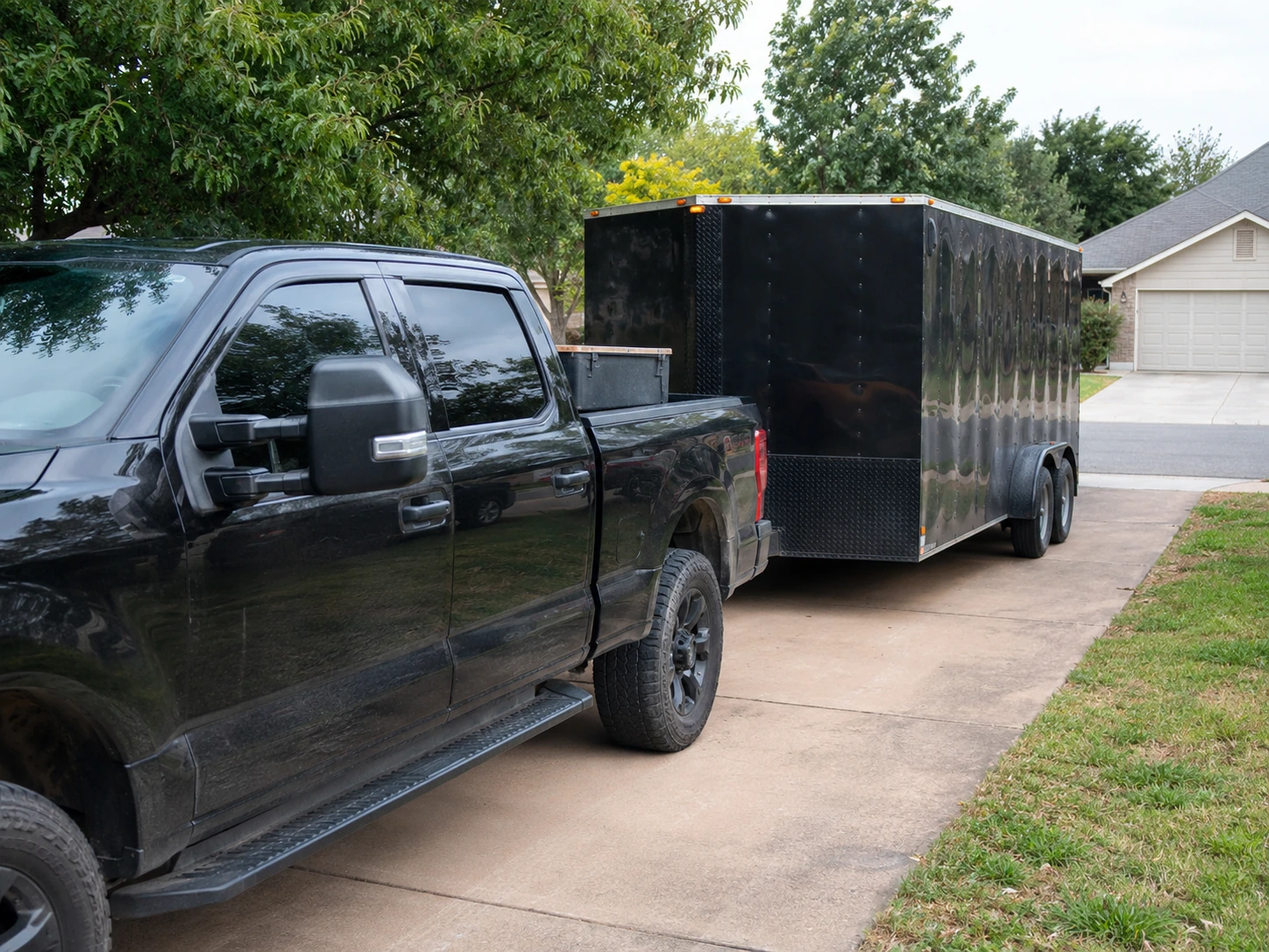 Example hauling setup showing a black pickup truck with an enclosed trailer parked on a residential driveway